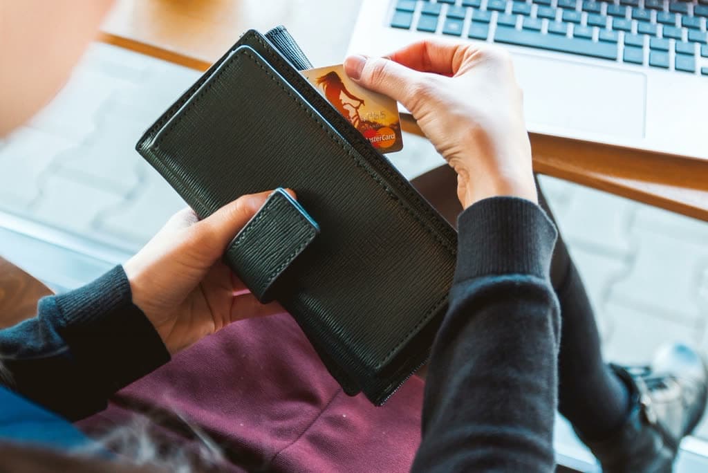 Paying for an online order with a card next to a laptop